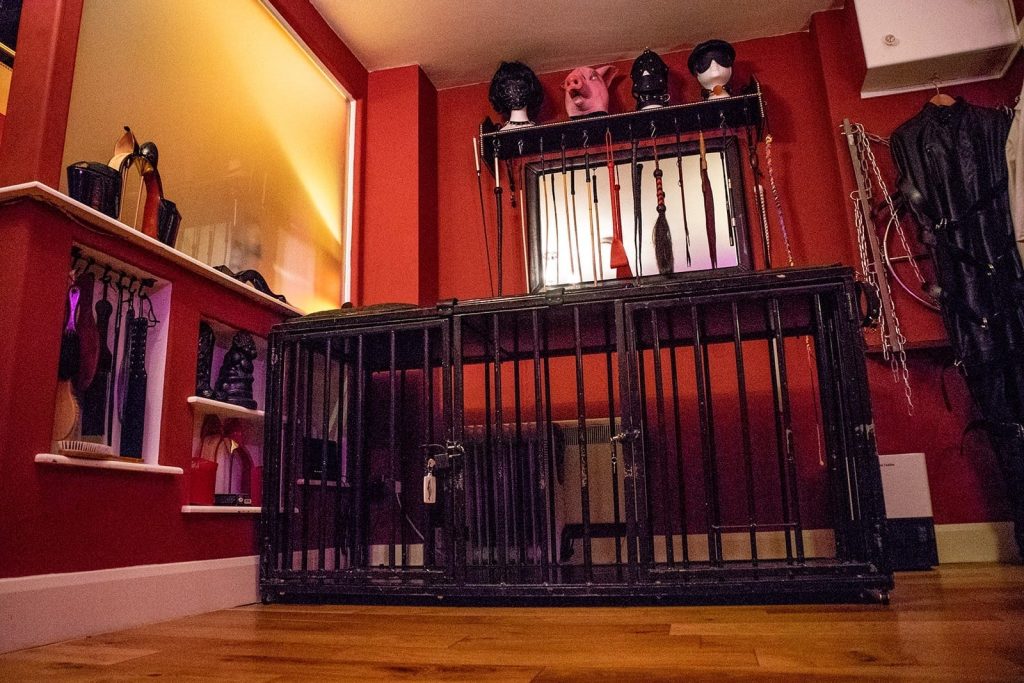 Steel cage bed under a shelf of hoods, with canes along the wall