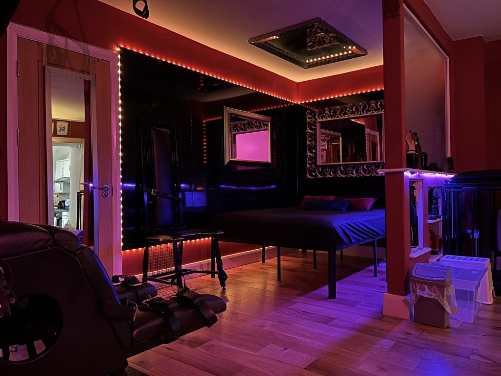Wide view of the bedroom with red LED trim, mirrors and bed