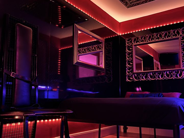 Bed with ornate mirror and red neon trim in the London BDSM hotel room
