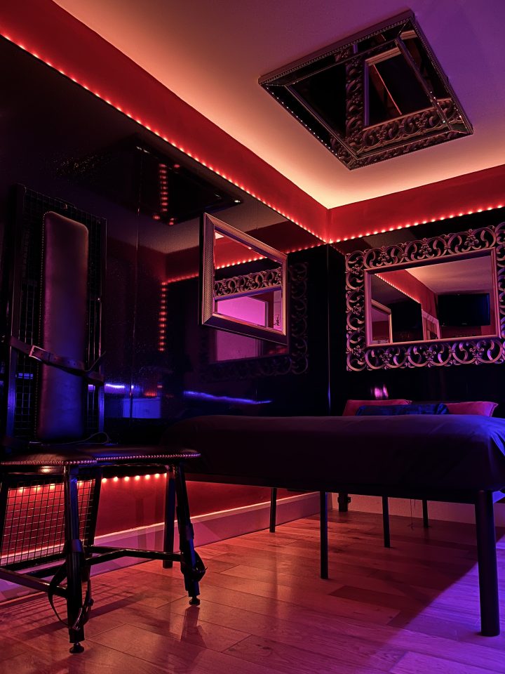 Bed with ornate mirror and red neon trim in the London BDSM hotel room