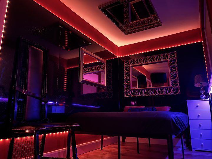 Dungeon bedroom with red LED ceiling, mirrors and four-poster style bed for overnight stays