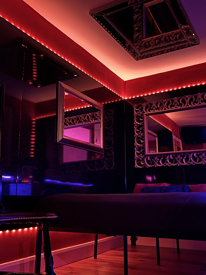 Dungeon bedroom with red LED ceiling, mirrors and four-poster style bed for overnight stays