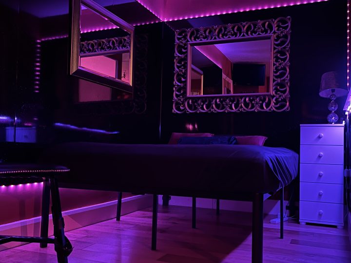 Overnight dungeon bedroom lit in purple with mirrored ceiling