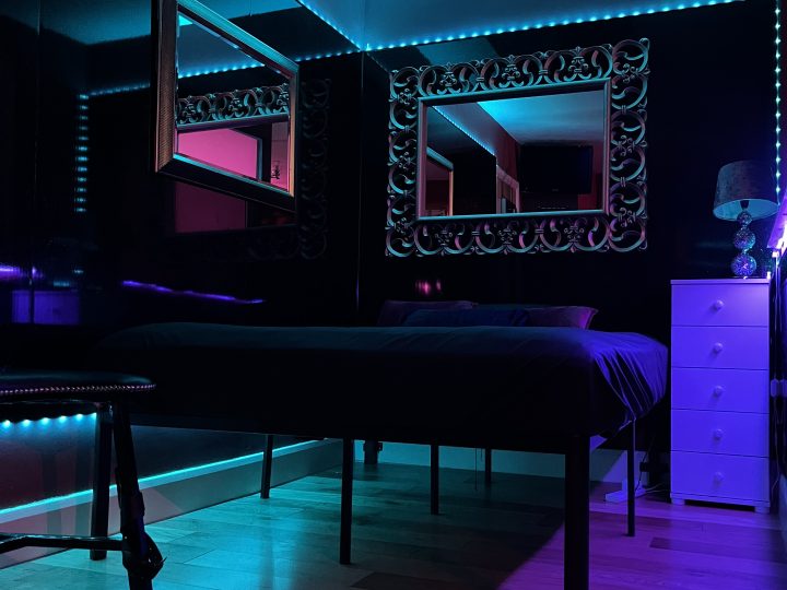 Kink hotel bedroom bathed in blue light at Bayswater Dungeon Suite
