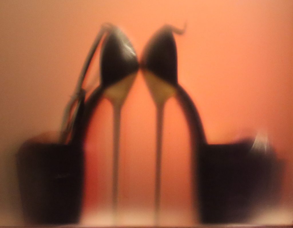 Silhouette of black platform stiletto heels against a warm orange backdrop