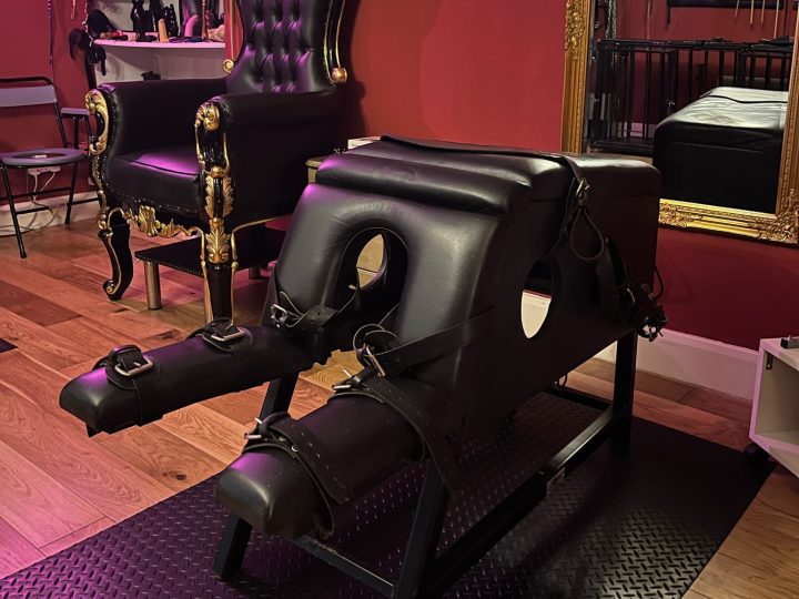 Padded leather bondage bench with restraints next to the throne