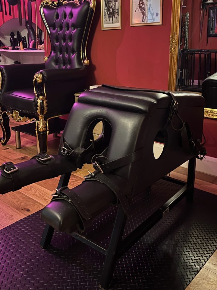 Padded leather bondage bench with restraints next to the throne