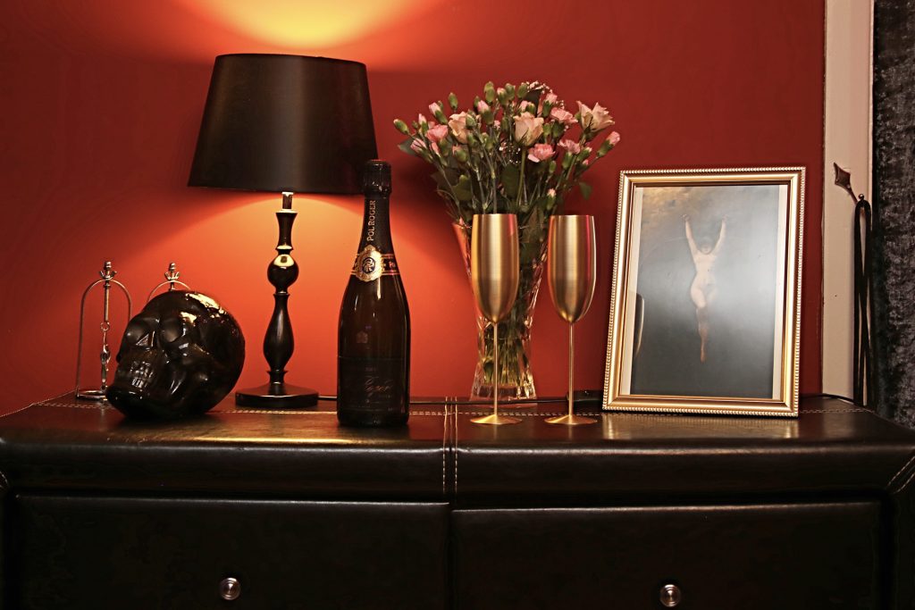 Black sideboard with lamp, skull ornament, flowers and a framed photograph