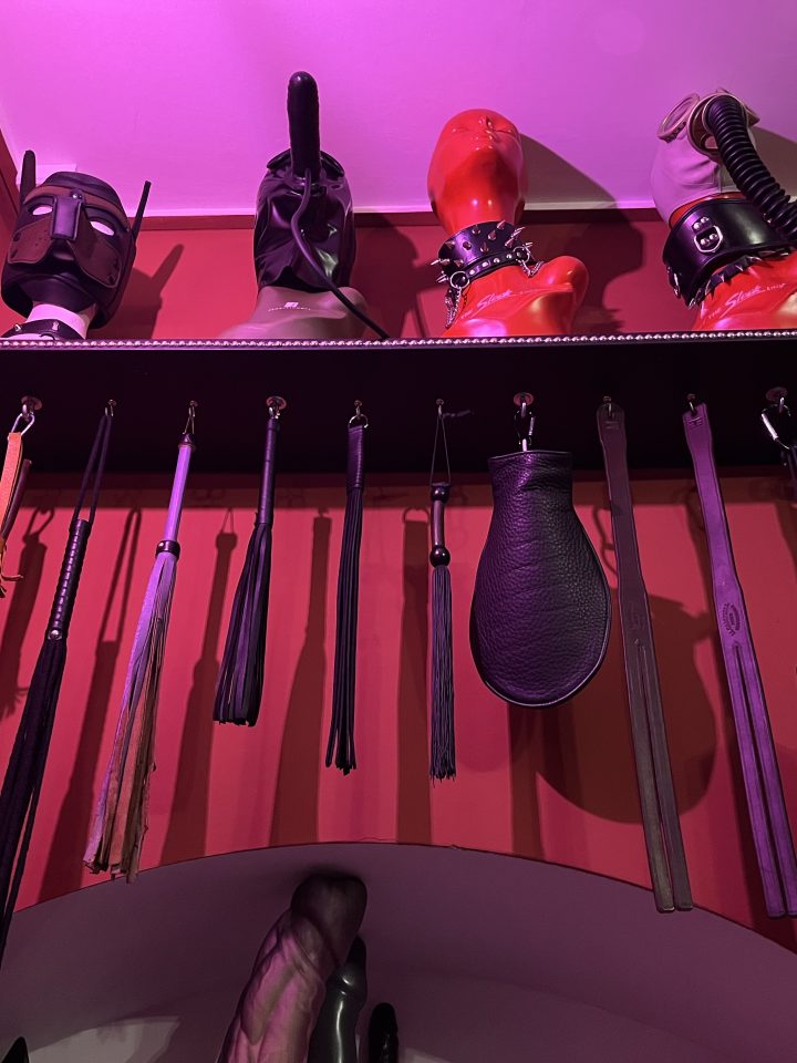 Close-up of floggers, crops and paddles on the dungeon wall