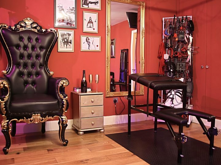 Black and gold dominatrix throne beside a spanking bench in the West London dungeon