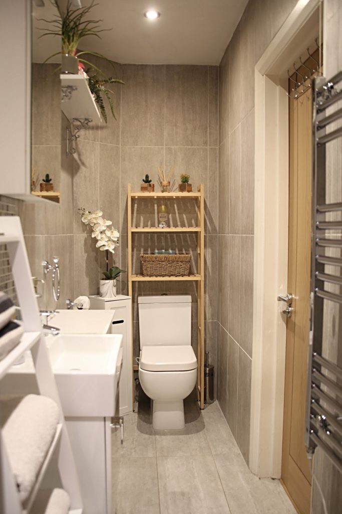 Private bathroom with basin, toilet and bamboo shelving