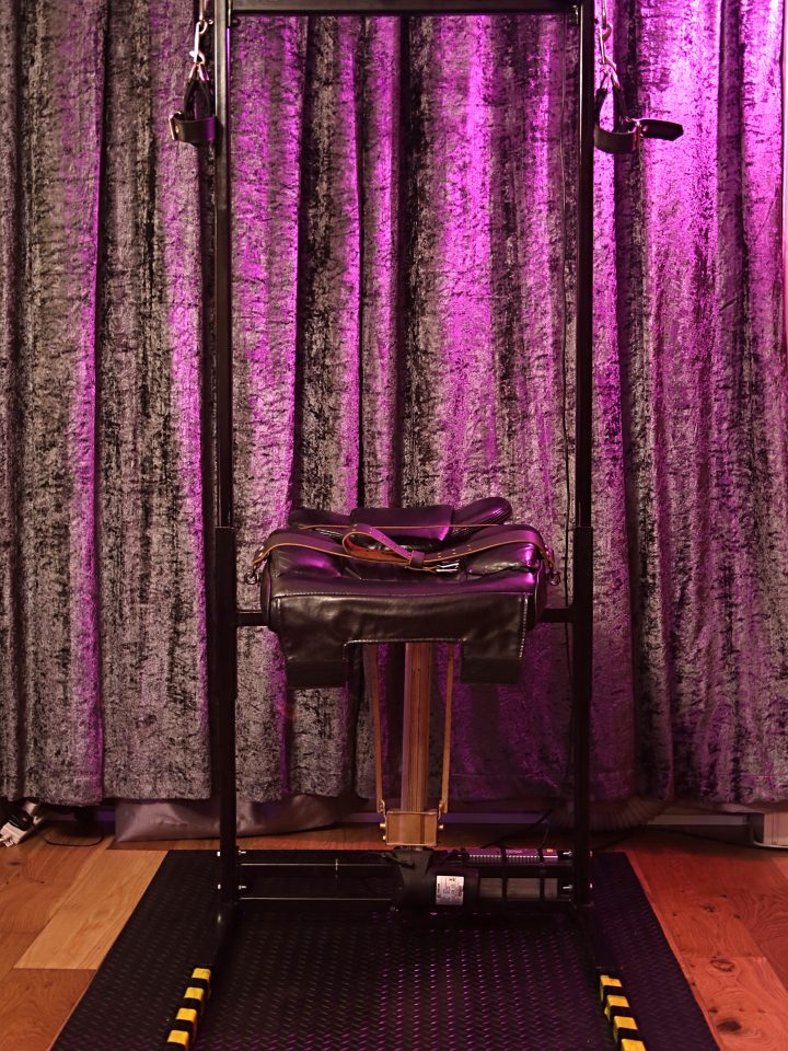 Leather smother chair with head sling in its steel frame against purple velvet curtains