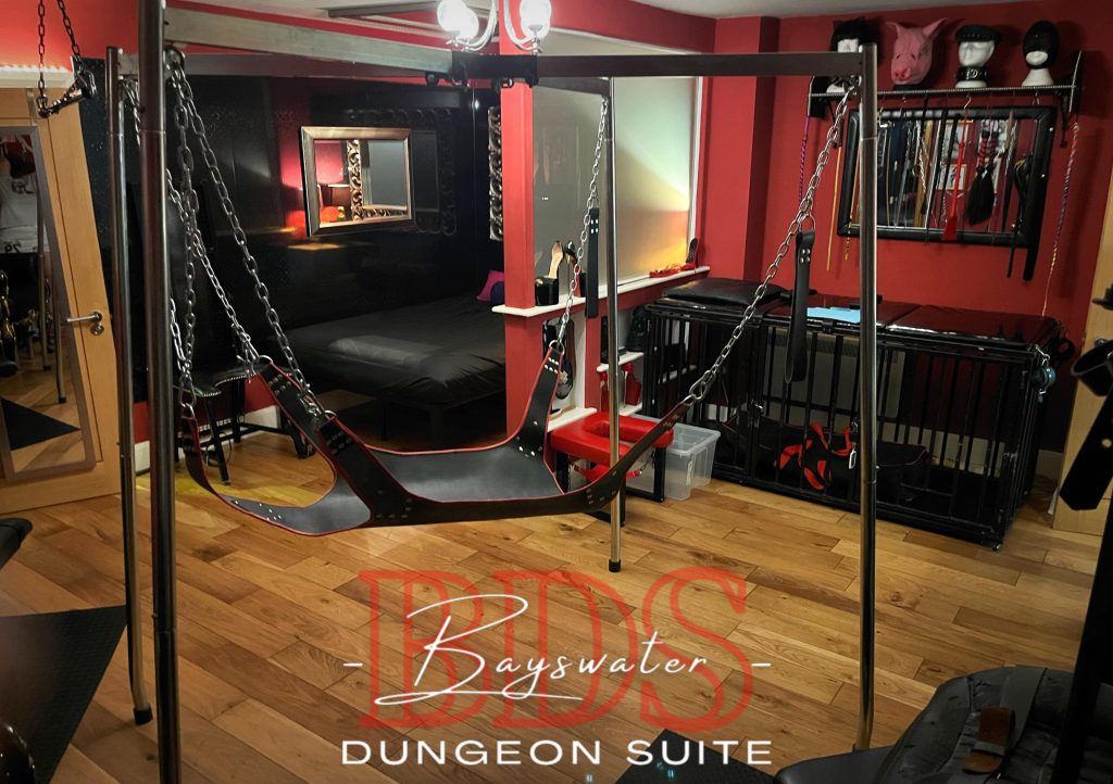 Steel sling frame with leather sling and chains, cage bed behind it