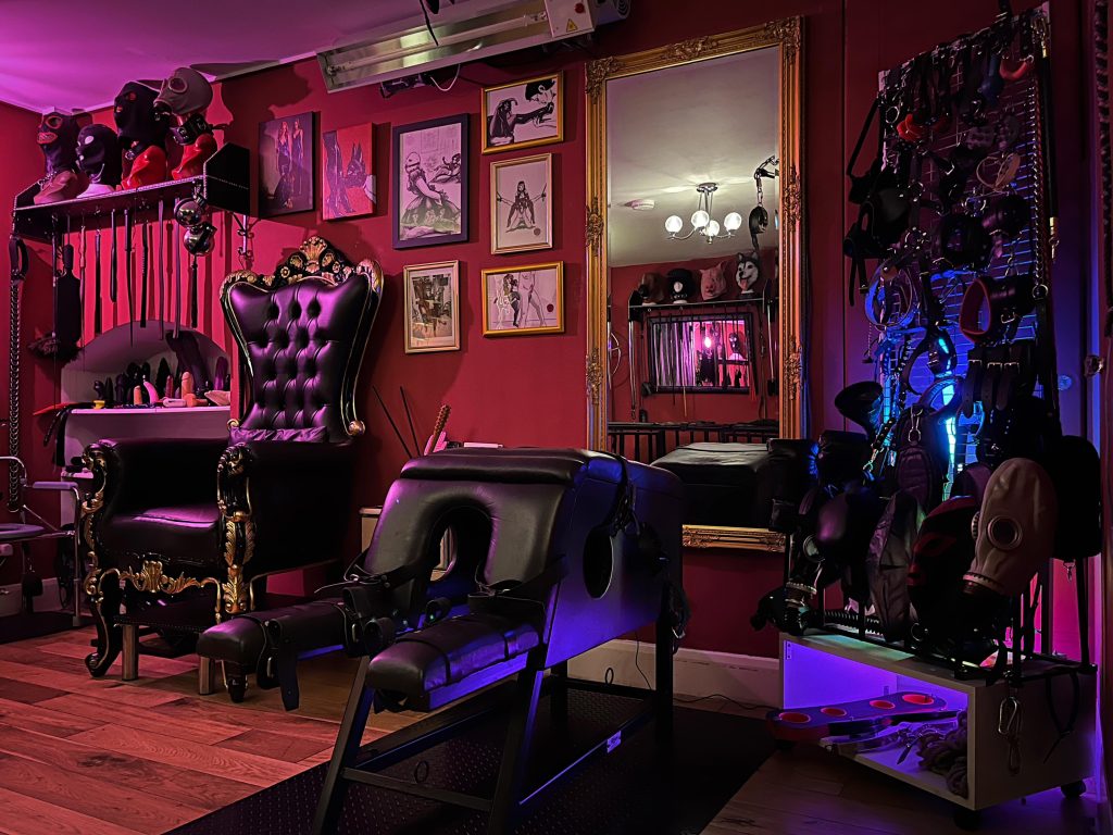 Leather spanking horse in front of the throne under pink and purple light