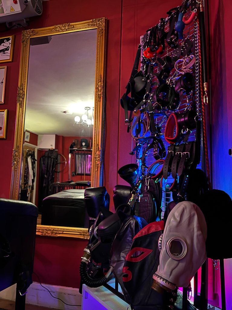 Gas masks and rubber hoods beside a gold mirror