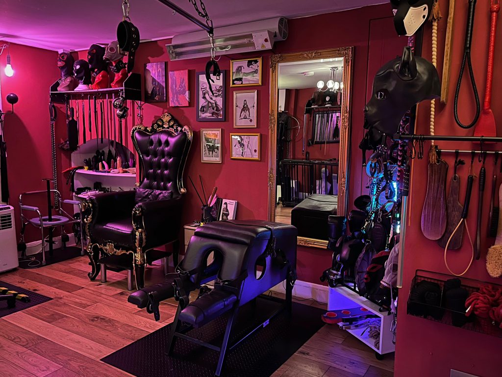 Throne corner with spanking horse, hoods and impact toys on the walls