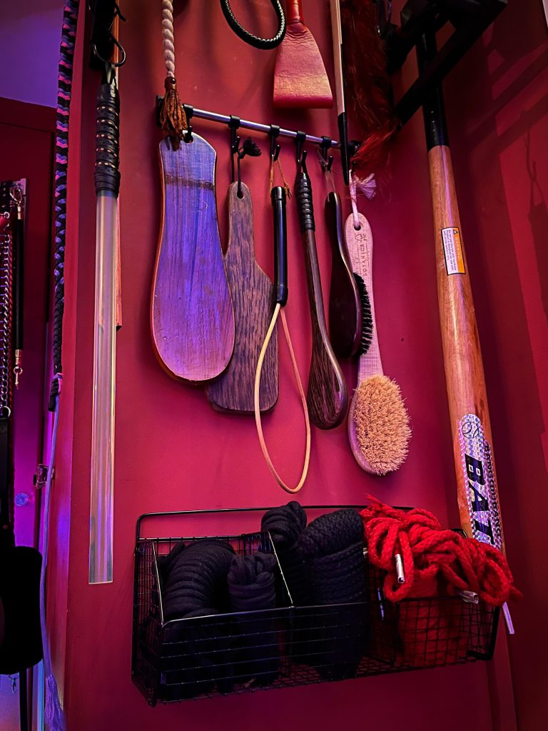 Paddles, wooden brush, hairbrush and red rope on hooks