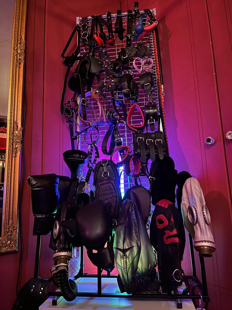 Display of rubber hoods and masks above gas masks on a lit stand